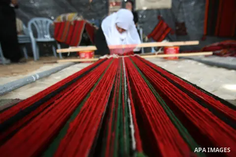 A Palestinian woman works on weaving machine during a takes part in the Spring Ramadeen festival, in Ramadeen village, south in the West Bank city of Hebron, on Apr. 13, 2013. Photo by Mamoun Wazwaz