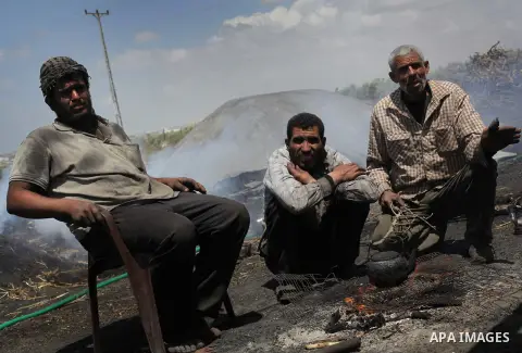 Palestinian workers take a break at one of the few local charcoal manufacturing shops east of Gaza City on April 16, 2013. In adapting to years of border blockades and shortages, Gazans have become experts at recycling a...