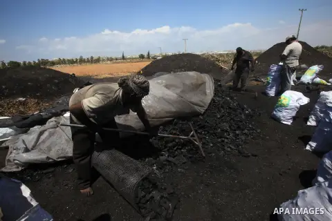 Palestinian workers fill bags with coal to be sold, at one of the few local charcoal manufacturing shops east of Gaza City on April 16, 2013. In adapting to years of border blockades and shortages, Gazans have become exp...