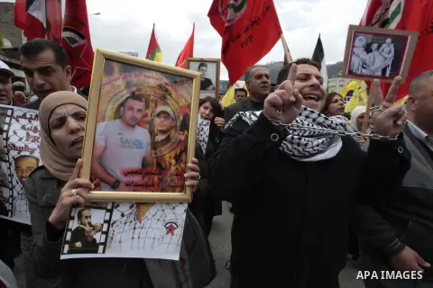 Palestinians carry portraits of prisoners while attending a rally to highlight the situation of some 4700 Palestinians currently jailed in Israel during a rally on the annual Palestinian Prisoners' Day, in West Bank city...