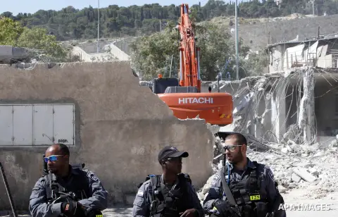Israeli soldiers stand guard as the bulldozers demolish a Palestinian house in Jerusalem on April 24, 2013. Jerusalem municipality demolished early today three apartments and three shops owned by Palestinians Khomeini Ha...