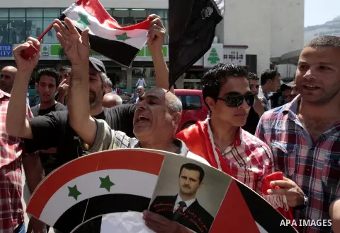 Palestinian pro-al-Assad regime activists hold pictures of Syrian president Bashar al-Assad and Syrian flags during a march in solidarity with the Syrian regime, in the West Bank city of Nablus May 06, 2013. The Damascus...