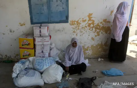 A Palestinian woman sits next to the food aid at the U.N. Relief and Works Agency, (UNRWA), warehouse in Deir al-Balah in the center of Gaza strip, May 07, 2013. The United Nations Relief and Works Agency, known as UNRWA...