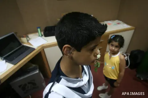 A Palestinian deaf boy shows his ear hearing aid at a deaf center in preparation for implant a cochlear, in Gaza city on May 27, 2013. Cochlear implants may help provide hearing in patients that are not deaf because of d...