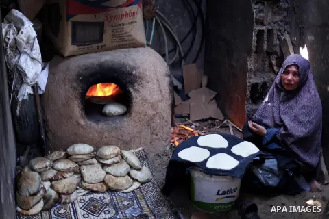 A Palestinian woman bakes bread on firewood outside her family house in Beit Lahiya town, North Gaza Strip, 28 May 2013. Photo by Ali Jadallah
