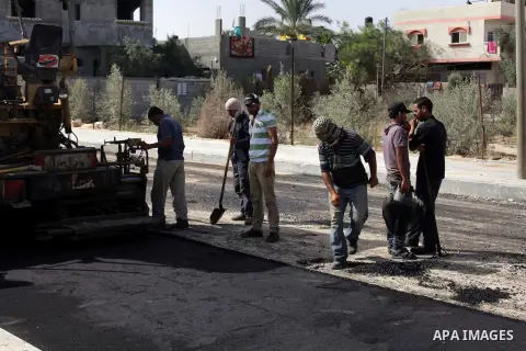 Palestinian workers lay asphalt as a street is paved in Deir al-Balah in central Gaza Strip, on May 29, 2013. Photo by Ashraf Amra