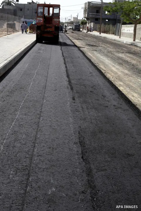 Palestinian workers lay asphalt as a street is paved in Deir al-Balah in central Gaza Strip, on May 29, 2013. Photo by Ashraf Amra