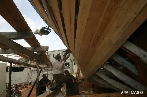 Abdullah al-Najjar, 55-years-old and his family construct a new fishing boat in front of his house on the seaside in the Rafah town in the southern Gaza Strip near the border with Egypt on June 9, 2013. Fishermen in Gaza...