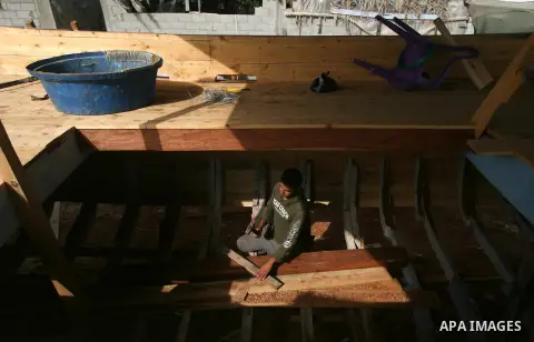 The son of Abdullah al-Najjar, 55-years-old, constructs a new fishing boat in front of his house on the seaside in the Rafah town in the southern Gaza Strip near the border with Egypt on June 9, 2013. Fishermen in Gaza s...