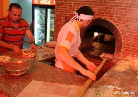 Palestinian Basem Shnar works at his small restaurant in Gaza City, on June 10, 2013. Shnar, a Palestinian who lived in Syria before the conflict took place there, now makes a living by selling pastries with Syrian flavo...