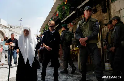 A Palestinian elderly woman walks past Israeli security guards following Friday prayers at al-Aqsa mosque, in Jerusalem's old city on June 21, 2013. A security guard shot and killed a Jewish Israeli man on Friday at one...