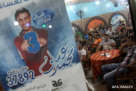 Palestinians watch Mohammad Assaf, a Palestinian finalist on the Arab Idol talent show, performing on the televison in Gaza City, June 22, 2013. Palestinians relished a rare moment of pride and national unity after the 2...