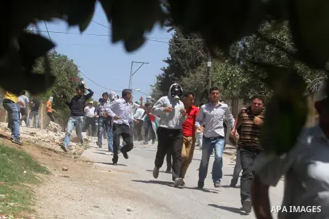 Palestinian protesters run seek for cover from tear gas fired by Israeli security forces during clashes following a protest against the expropriation of Palestinian land by Israel in the village of Kfar Qaddum near the o...