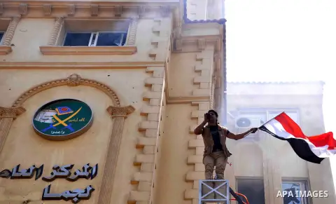 An Egyptian man carries his national flag as he stands on the wall at the Muslim Brotherhood's national headquarters after it was attacked in the al-Moqattam suburban, Cairo, Egypt, 01 July 2013. Medics said at least 12...