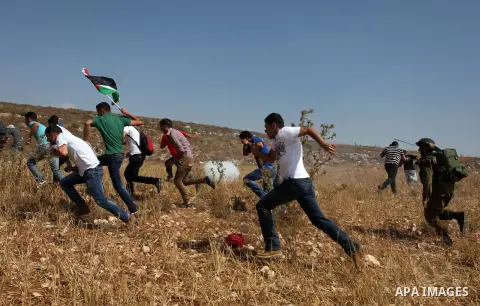 An Israeli seurity officer runs after Palestinian protesters during a demonstration against the expropriation of Palestinian land by Israeli settlement of Beit El, near the West Bank village of Beitin northeast city of R...