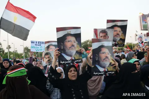 Ousted President Mohamed Morsi supporters and Muslim brotherhood members shout political and hold placards in his support as they demonstrate against his toppling at Raba al-Adawyia mosque on July 7, 2013 in Cairo. Carry...
