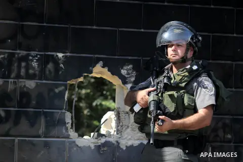 An Israeli security, guards the holes knocked through part of Israel's controversial separation barrier by Palestinian youth, in the Abu Dis neighborhood, bordering Jerusalem, on July 9, 2013. Israel says the barrier is...