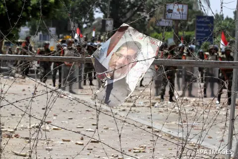 A poster of deposed president Mohamed Morsi hangs on barbed wire that blocks the access to the headquarters of the Republican Guard in Cairo on July 9, 2013. Egypt's armed forces warned in a statement against any attempt...