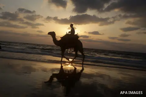 A Palestinian enjoys riding a camel in the sea at Gaza beach on July 9, 2013. ahead of the Muslim holy fasting month Ramadan. Photo by Ashraf Amra