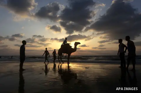 A Palestinian enjoys riding a camel in the sea at Gaza beach on July 9, 2013. ahead of the Muslim holy fasting month Ramadan. Photo by Ashraf Amra