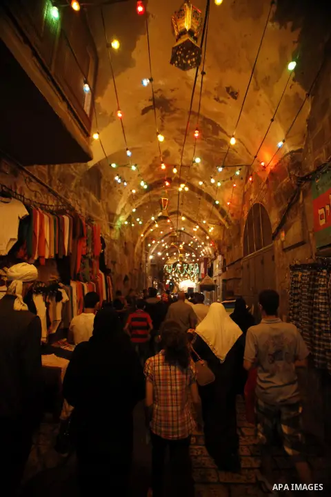 Palestinians walk in an illuminated street before attending the Taraweeh prayer at the al-Aqsa mosque compound in the old city of Jerusalem after breaking the fast on the First day of the Moslem holy month of Ramadan on...