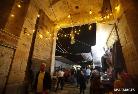 Palestinians walk in an illuminated street before attending the Taraweeh prayer at the al-Aqsa mosque compound in the old city of Jerusalem after breaking the fast on the First day of the Moslem holy month of Ramadan on...