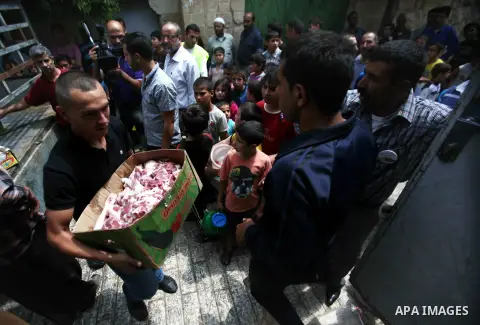 Palestinians receive donated food from an Islamic charity on the second day of the Muslim holy month of Ramadan, in the West Bank city of Hebron, on July 11, 2013. Devout Muslims refrain from eating, drinking and smoking...