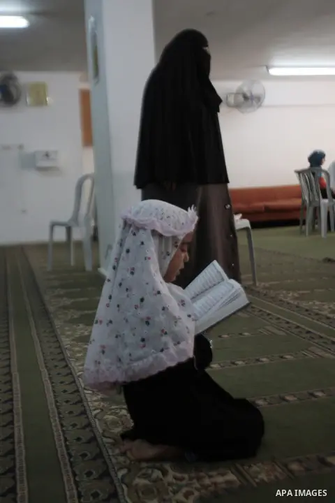 A Palestinian girl reads verses from the Koran, Islam's holy book, at a mosque on the second day of the Muslim fasting month of Ramadan on July 11, 2013 in the West bank city of Nablus. During Ramadan, one of the five ma...