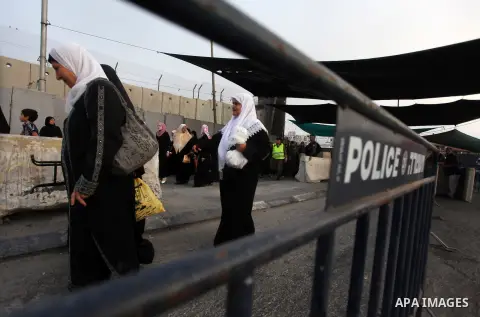 Palestinian women cross the Qalandia checkpoint on their way to pray at the al-Aqsa Mosque during the Muslim holy month of Ramadan, at the Qalandia checkpoint between the West Bank city of Ramallah and Jerusalem, Friday,...
