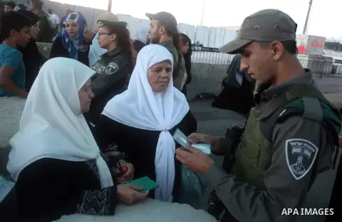 Palestinian women cross the Qalandia checkpoint on their way to pray at the al-Aqsa Mosque during the Muslim holy month of Ramadan, at the Qalandia checkpoint between the West Bank city of Ramallah and Jerusalem, Friday,...