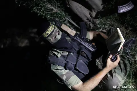 A Masked militant from al-Quds Brigades the armed wing of the Islamic Jihad organization, reads holy Quran during a guard the eastern border of Gaza City, on July 15, 2013. Photo by Ashraf Amra