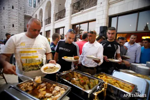 Palestinian Muslims take part in the Iftar ceremony (the evening meal during the Islamic month of Ramadan), organised by the association of development of Christians neighborhood, in Jerusalem on July 25, 2013. Photo by...