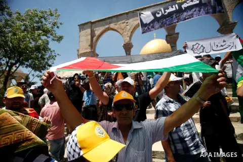Palestinians hold their national flag during a protest in solidarity with prisoners in Israeli jails after Friday prayers in front of the Dome of the Rock on the compound known to Muslims as Noble Sanctuary and to Jews a...