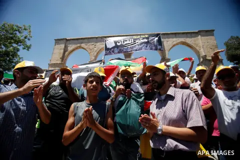 Palestinians hold their national flag during a protest in solidarity with prisoners in Israeli jails after Friday prayers in front of the Dome of the Rock on the compound known to Muslims as Noble Sanctuary and to Jews a...