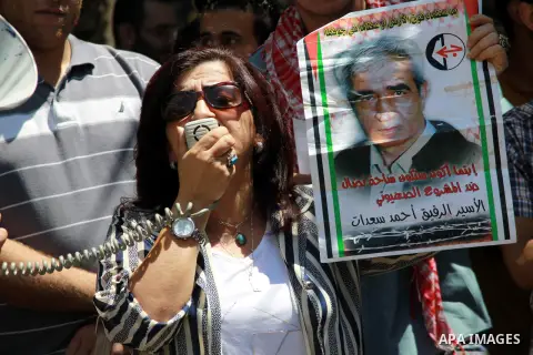 Palestinians hold a poster of Ahmed Saadat, a leader of the Popular Front for the Liberation of Palestine, imprisoned by Israeli during a protest in the town of Nablus in the West Bank on Tuesday, July 30, 2013. PFLP sup...