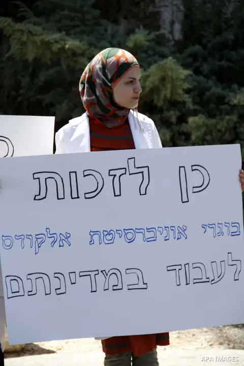 A Palestinian student of medical colleges in Jerusalem's al-Quds University holds a placard during a protest against the Israeli Health ministry demanding to confess of their certificates and allow them to work in Israel...