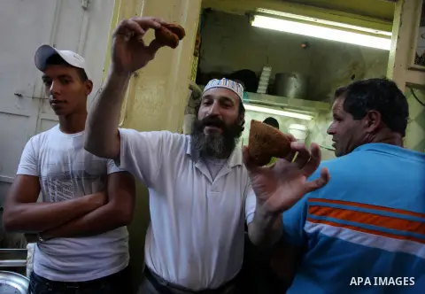 A Palestinian man sells falafel in front of Damascus gate during Muslim fasting month of Ramadan, in Jerusalem's old city, Aug 02, 2013. While fasting from dawn until sunset, Muslims refrain from consuming food, drinking...