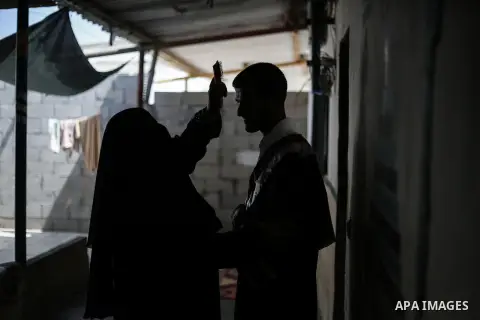 The mother of Fadi al-Shami, 21, a Palestinian blind youth, combs her son's hair before his graduation ceremony at their home in Central Gaza Strip on Aug 17, 2013. al-Shami lost his sight after he was injured by an Isra...