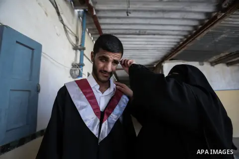 The mother of Fadi al-Shami, 21, a Palestinian blind youth, combs her son's hair before his graduation ceremony at their home in Central Gaza Strip on Aug 17, 2013. al-Shami lost his sight after he was injured by an Isra...