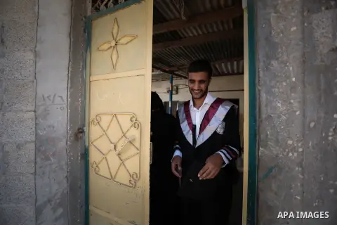 Fadi al-Shami, 21, a Palestinian blind youth, leaves his home to attend the graduation ceremony at his family home in Central Gaza Strip on Aug 17, 2013. al-Shami lost his sight after he was injured by an Israeli airstri...
