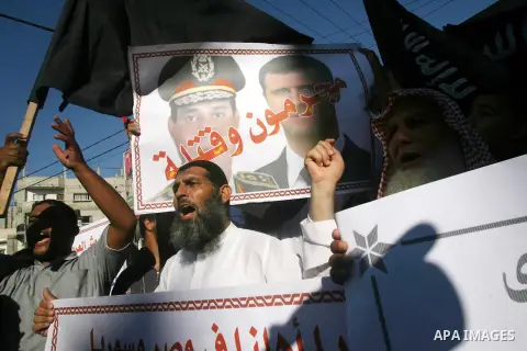 A Palestinian Salafist holds a poster depicting Syria's President Bashar al-Assad (R) and Egypt's army chief General Abdel Fattah al-Sisi with the Arabic words reading "Criminals and murderers", during a rally in protest...