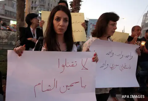 Palestinians hold placards during a vigil to show solidarity with Syrian civilians after hundreds were killed on Wednesday in rebel-held Damascus suburbs, in the West Bank city of Ramallah August 22, 2013. Some 30 Palest...