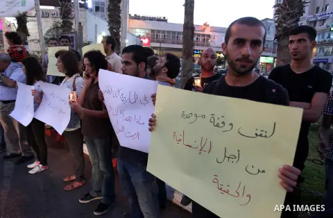 Palestinians hold placards during a vigil to show solidarity with Syrian civilians after hundreds were killed on Wednesday in rebel-held Damascus suburbs, in the West Bank city of Ramallah August 22, 2013. Some 30 Palest...