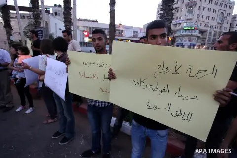 Palestinians hold placards during a vigil to show solidarity with Syrian civilians after hundreds were killed on Wednesday in rebel-held Damascus suburbs, in the West Bank city of Ramallah August 22, 2013. Some 30 Palest...
