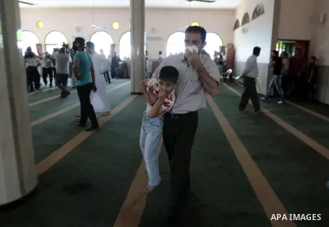 A Palestinian man carries his son as he suffering from tear gas fired by Israeli security forces at a mosque during Friday prayer in the village of Kfar Qaddum, near Nablus in the occupied West Bank on August 13, 2013. P...