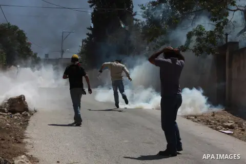A Palestinian protester kicks back a tear gas canister fired by Israeli security forces during clashes following a protest against the expropriation of Palestinian land by Israel in the village of Kfar Qaddum, near Nablu...