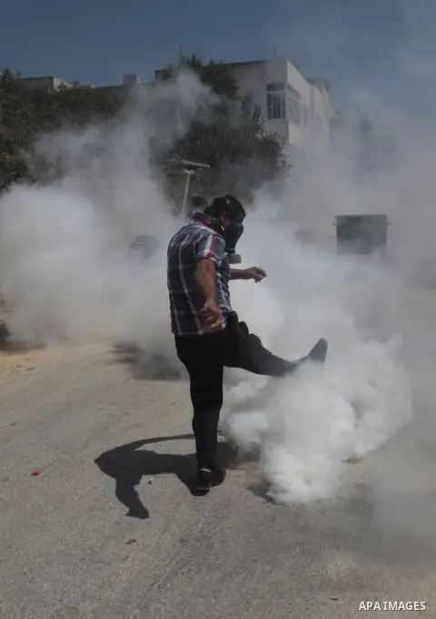 A Palestinian protester kicks back a tear gas canister fired by Israeli security forces during clashes following a protest against the expropriation of Palestinian land by Israel in the village of Kfar Qaddum, near Nablu...