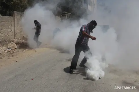 A Palestinian protester kicks back a tear gas canister fired by Israeli security forces during clashes following a protest against the expropriation of Palestinian land by Israel in the village of Kfar Qaddum, near Nablu...