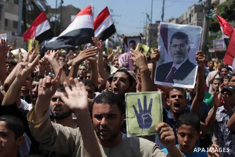 Palestinians hold Egyptian national flags, posters of ousted Egyptian President Mohamed Morsi and logos of four fingers, during a demonstration to support Morsi and denounce Syria's President Bashar al-Assad, in Al-Nusir...