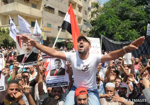 Egyptians supporters of ousted president Morsi hold posters depicting him and others depicting a hand in a sign of the number four during a Friday protest called for by the Muslim Brotherhood in Helwan, Egypt, 23 August...
